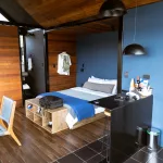 Modernes Hotelzimmer im Boato Hotel in Guatapé, Kolumbien, mit gemütlichem Bett, Holzinterieur und offenem Badezimmerbereich.