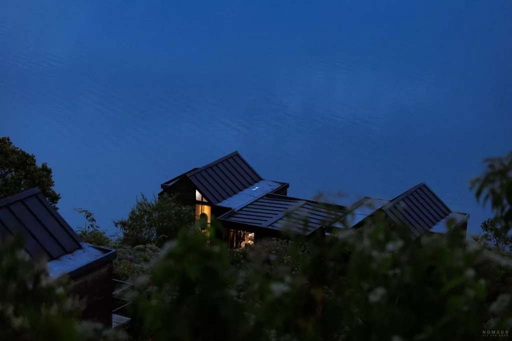 Abendansicht des Boato Hotels in Guatapé, Kolumbien, mit modernen Hütten am Seeufer und warm beleuchtetem Fenster.