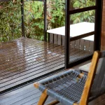 Holzterrasse und moderner Stuhl im Boato Hotel in Guatapé, Kolumbien, mit Blick ins Grüne nach einem Regenschauer.