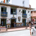 Fassade des Palacio Municipal in Guatapé, Kolumbien, mit bunten Holzverzierungen und Menschen vor dem Eingang.
