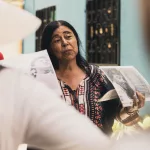 Frau in Medellín erzählt während einer Stadtführung von der Geschichte Kolumbiens und zeigt Fotos aus der Vergangenheit.
