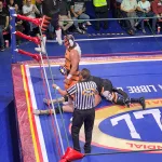 Luchadores beim Kämpfen im Ring, während einer am Boden liegt und festgehalten wird, daneben der Schiedsrichter