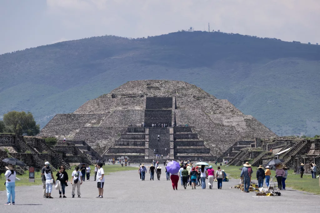 Blick auf die Mondpyramide in Teotihuacán von der Straße der Toten aus – mit Besuchergruppen im Vordergrund und Bergen im Hintergrund