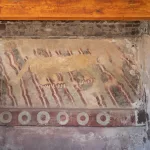 Gut erhaltene prähispanische Wandmalerei (Mural del Puma) eines gelblichen Pumas mit roten Krallen auf einem Hintergrund aus wellenförmigen Linien in Rot und Grün, entdeckt in einer Residenz in Teotihuacán.