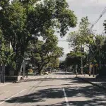 Breite, von Bäumen gesäumte Straße im Stadtteil Laureles in Medellín – ruhige Atmosphäre mit Schattenplätzen, kleinen Geschäften und Cafés.