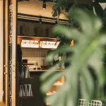 Ein Blick in ein stilvolles Café in Medellín mit Kaffeemaschine, Bohnenregalen und viel Grün.