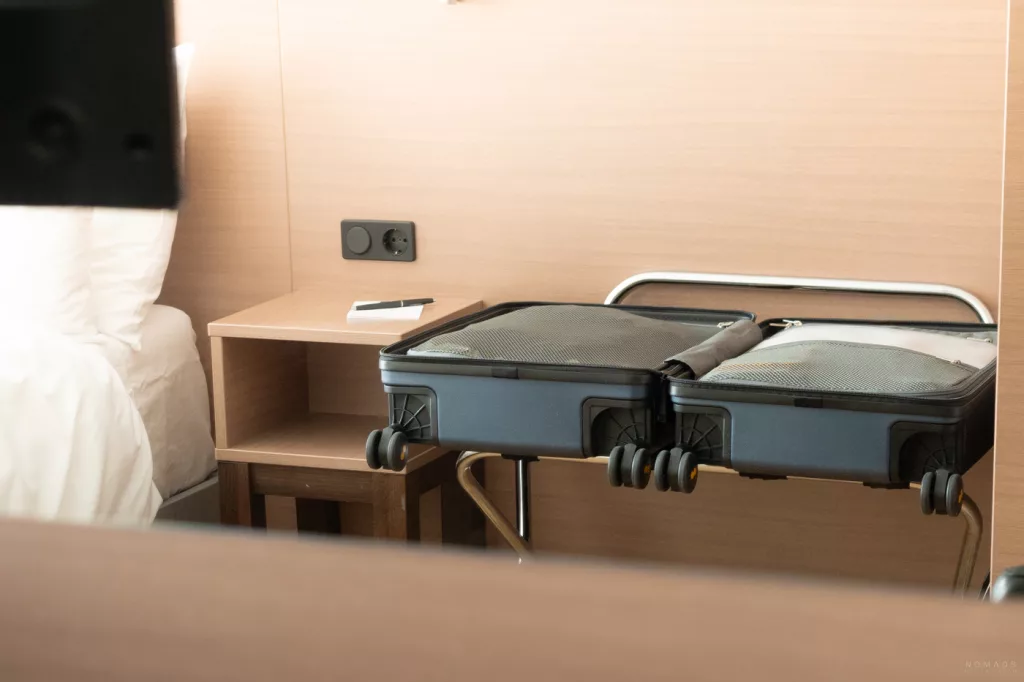 Geöffneter Level8 Handgepäckkoffer im Hotelzimmer, sichtbar mit Packfächern und Rollen.
