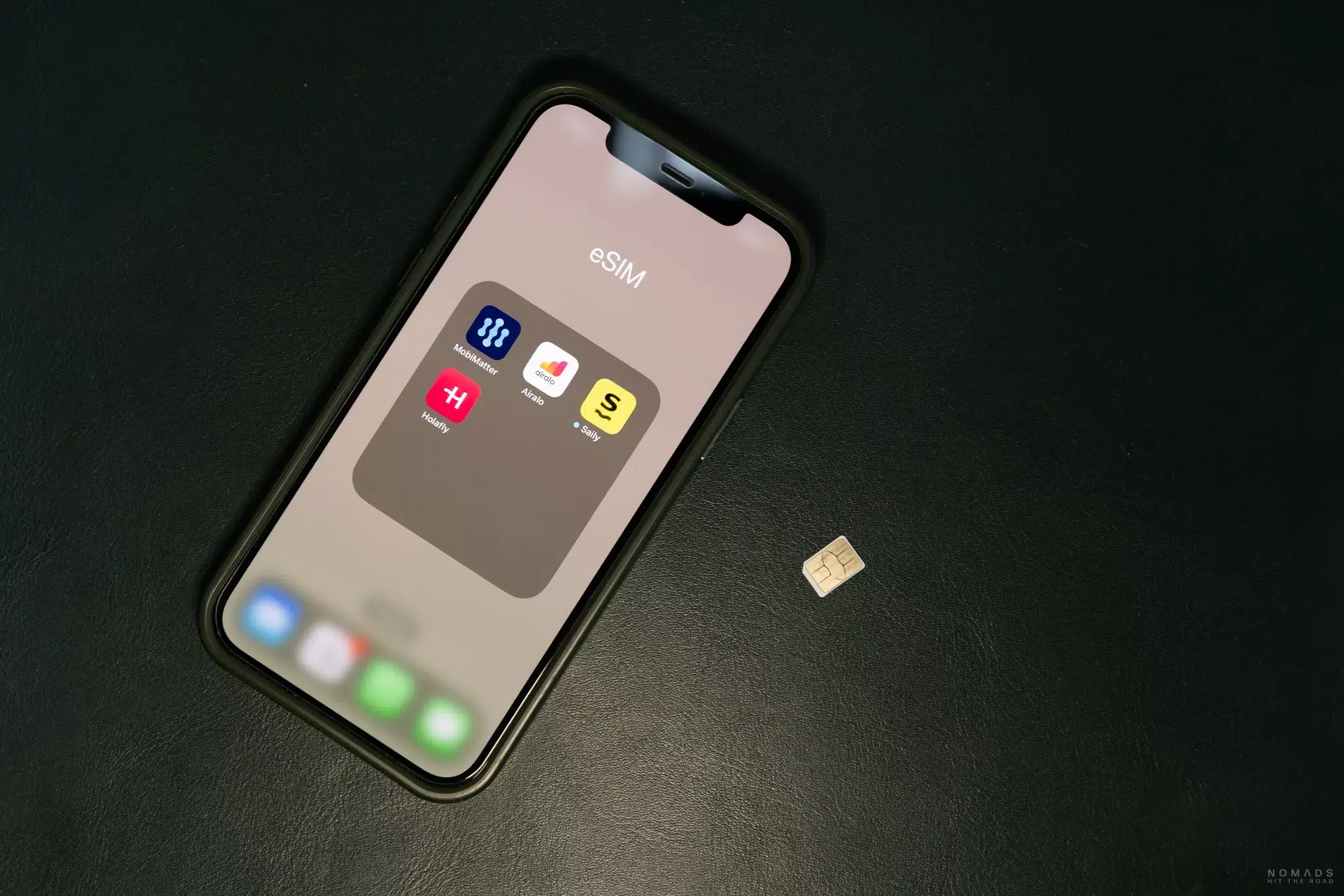 eSIM Apps auf einem Handy sind geöffnet während daneben eine physische SIM Karte liegt
