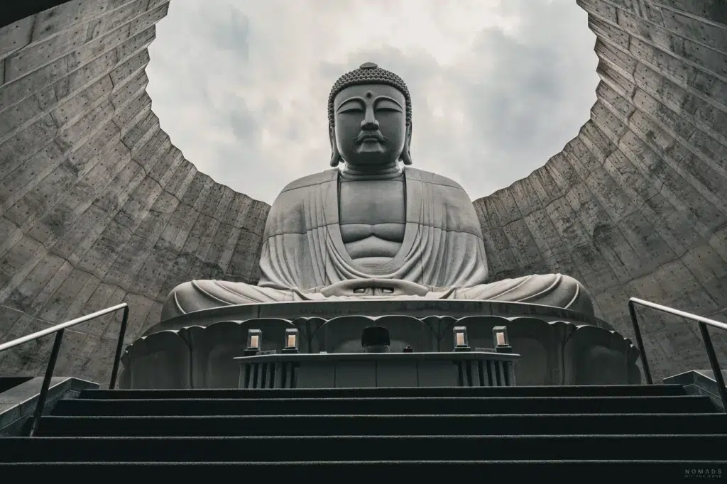 Frontale Perspektive auf die eindrucksvolle Buddha-Statue, umgeben von einem modernen Betonbau, im Makomanai Takino Cemetery in Sapporo.