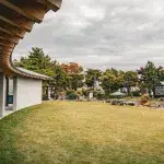 Ansicht eines überdachten Ganges mit geschwungener Dachkonstruktion, der in den japanischen Garten des Makomanai Takino Cemetery führt.