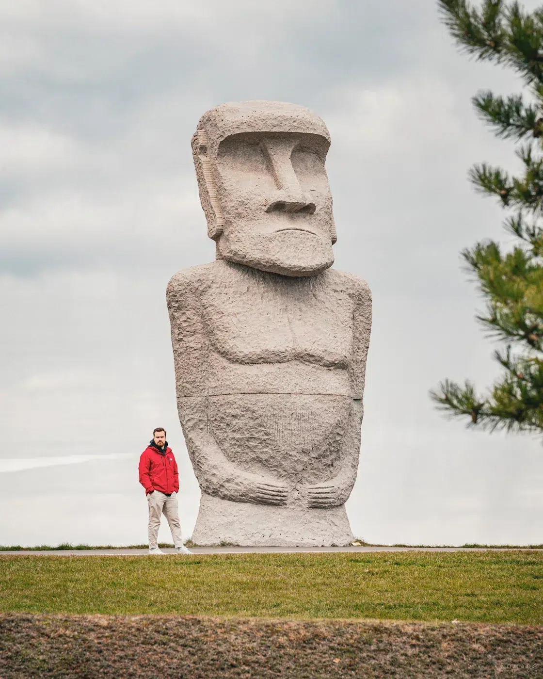 Große steinerne Moai-Statue mit einer Person in roter Jacke davor im Makomanai Takino Cemetery – ein ungewöhnlicher Anblick in Japan.
