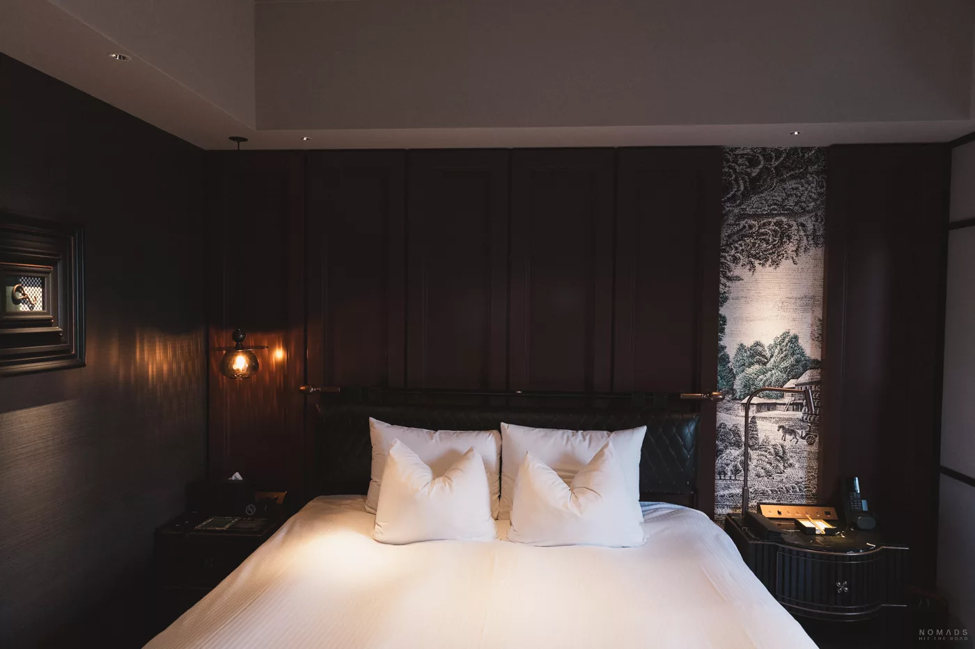 Elegantes Hotelzimmer im Hotel Sosei Sapporo – MGallery Collection mit einem großen Bett, weißen Kissen, dunkler Holzverkleidung und stilvoller japanischer Wandkunst im Hintergrund.