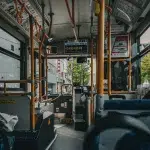 Blick aus dem hinteren Teil eines Stadtbusses in Sapporo mit typischer Ausstattung, Haltestellenanzeige und herbstlicher Straßenszene draußen.