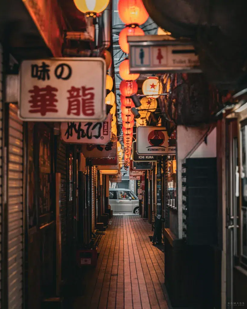 Schmale Gasse der Ramen Alley in Sapporo bei Abendlicht, mit roten Laternen und dicht gedrängten Leuchtreklamen – bekannt für ihre traditionellen Ramen-Lokale.
