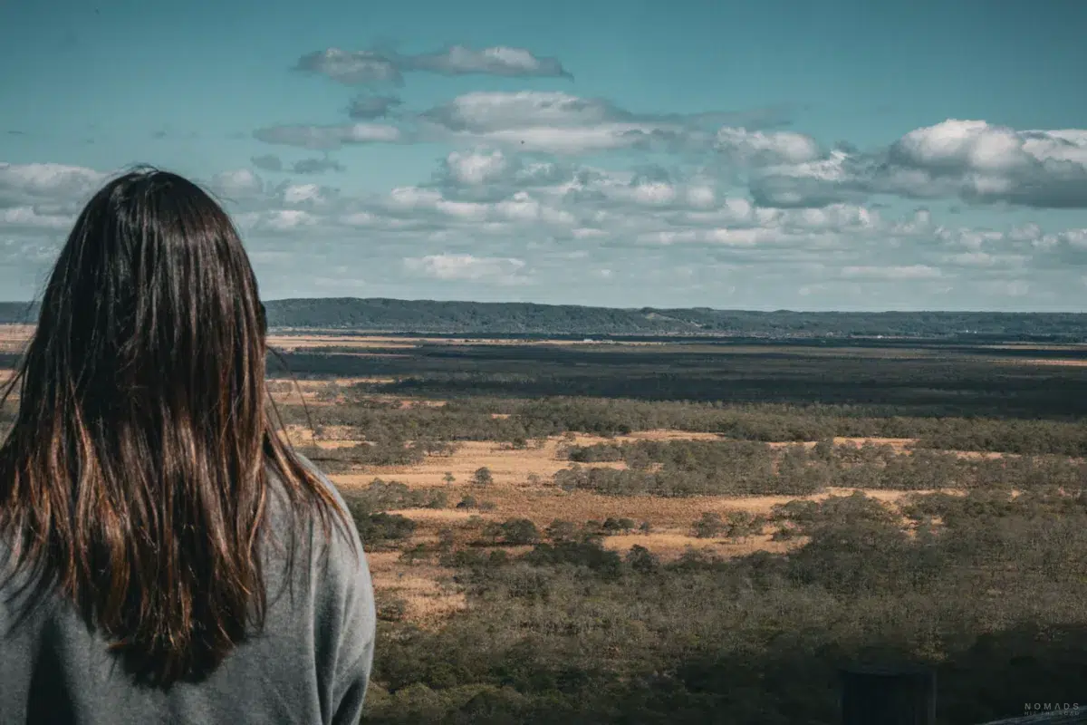 Rückenansicht einer Frau, die vom Aussichtspunkt des Kushiro Marsh Observatory auf das endlose Marschland blickt.