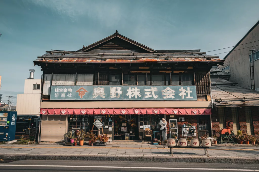 Historisches japanisches Holzgebäude mit verblasstem Firmenschild und kleinem Laden im Erdgeschoss in Otaru.