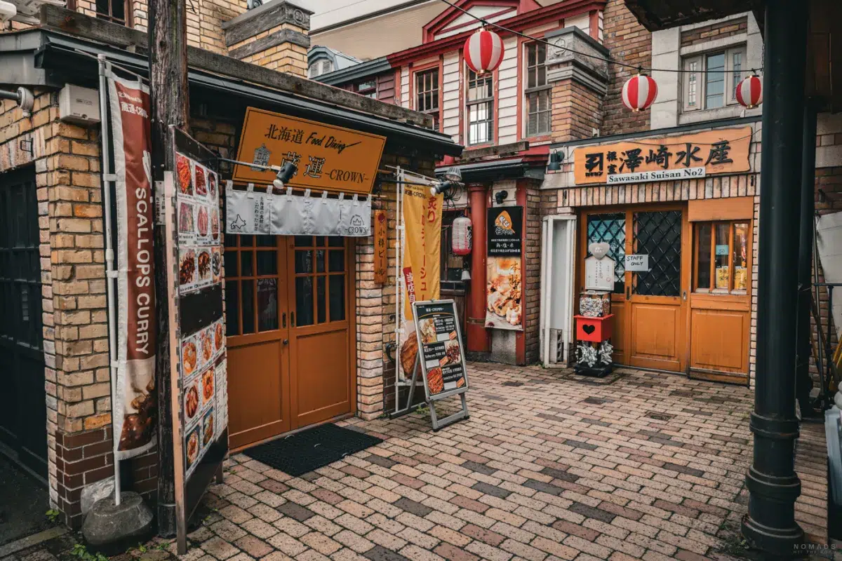 Kleine Restaurants und Imbissläden in Otaru Denuki Koji mit typischen Laternen und Speisekarten in einer engen Gasse.