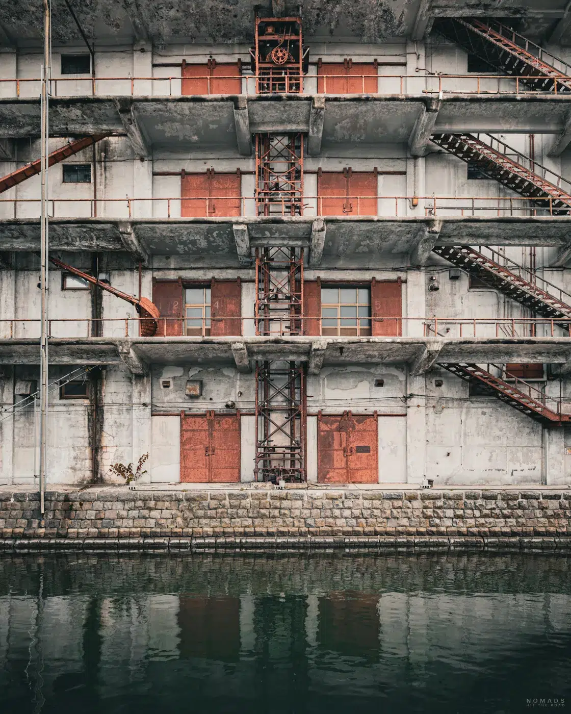 Frontansicht des historischen Warehouse No. 3 in Otaru, mit roten Luken, Metallkonstruktionen und Spiegelung im Kanal.