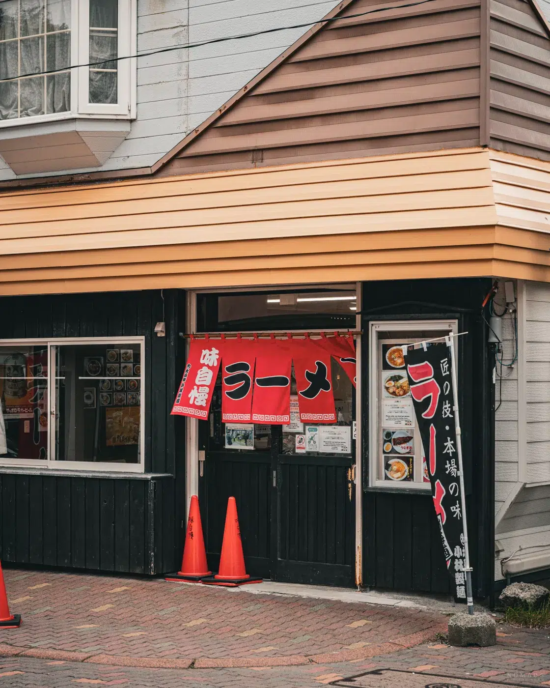Außenansicht des Ramen-Restaurants Ajiman in Noboribetsu mit rotem Noren-Vorhang und japanischer Beschilderung.