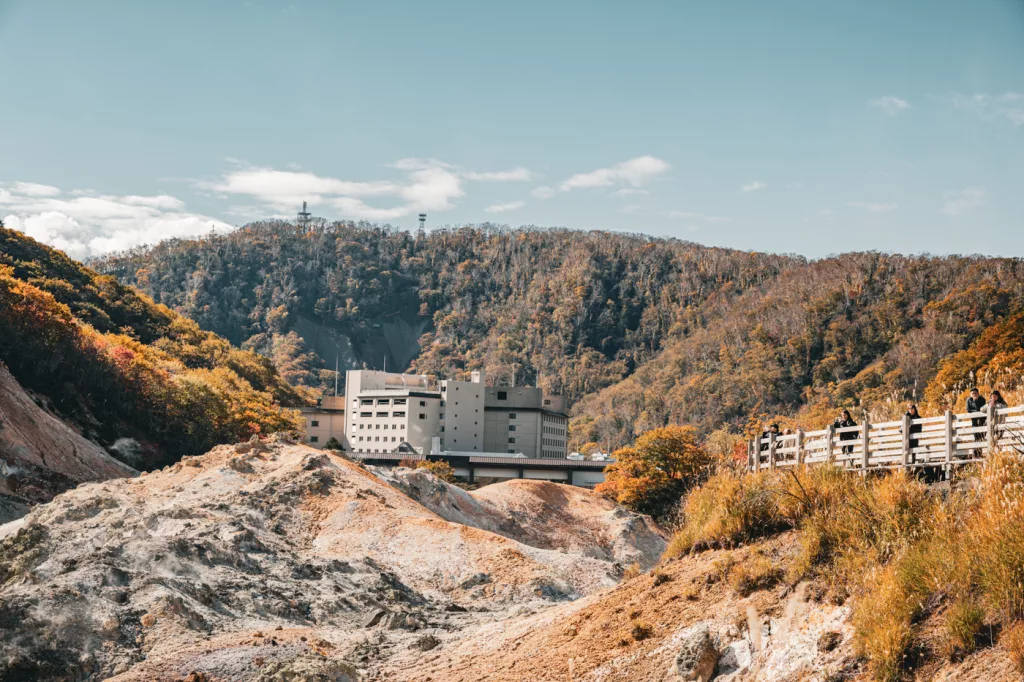 Blick über das Jigokudani Valley in Noboribetsu mit Onsen-Hotels im Hintergrund und herbstlicher Landschaft