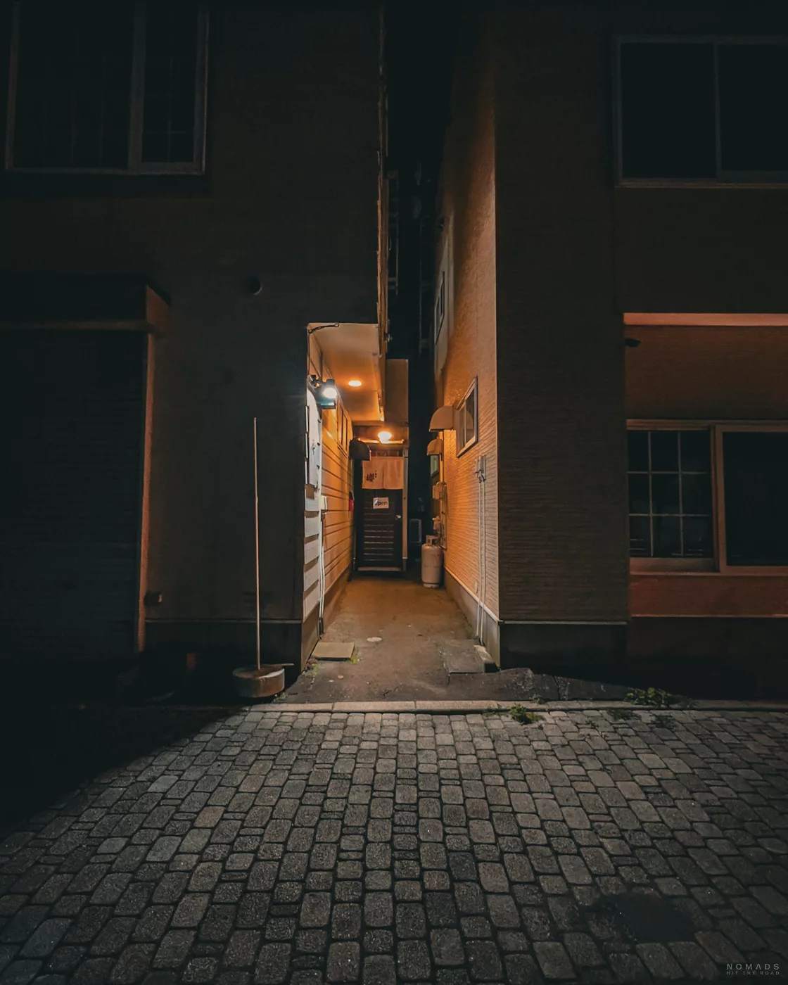 Schmaler, beleuchteter Eingangsbereich des Restaurants Oshokuji Sakura in Noboribetsu am Abend.