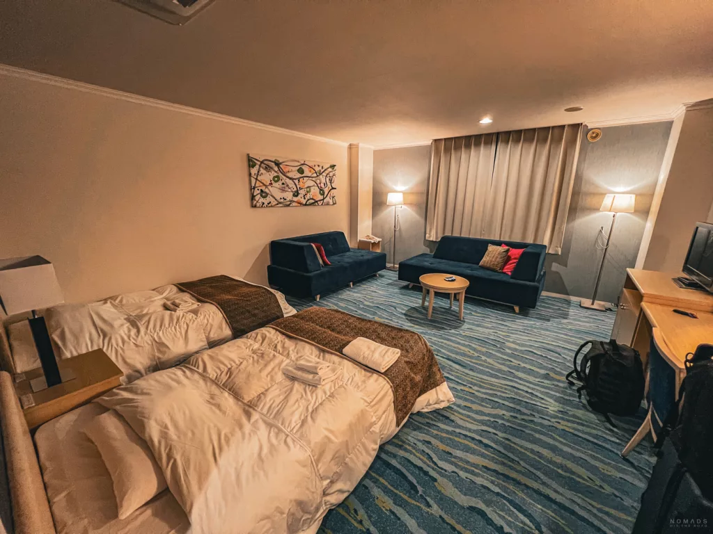 Großzügiges Hotelzimmer in Shiretoko mit zwei Einzelbetten, Sofa, Teppichboden und Sitzbereich – typisch japanische Einrichtung mit viel Platz und warmem Licht.