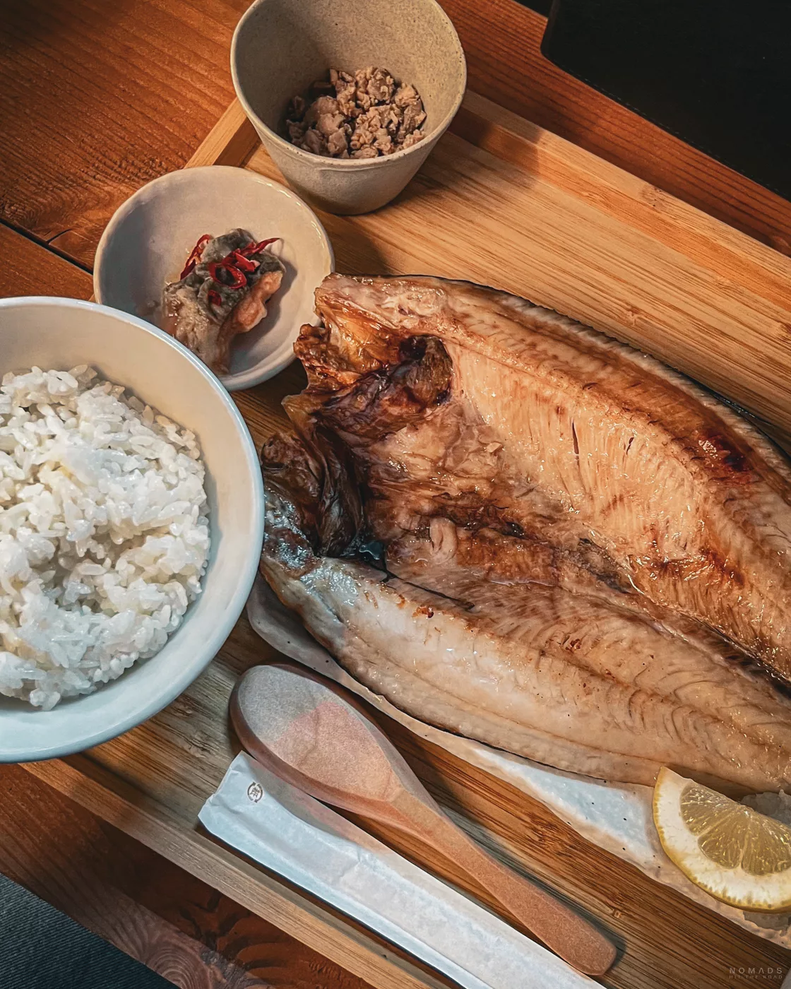 Gegrilltes Fischfilet mit Reis, kleinen Beilagen und Zitrone, serviert auf einem Holztablett in einem Restaurant in Utoro.