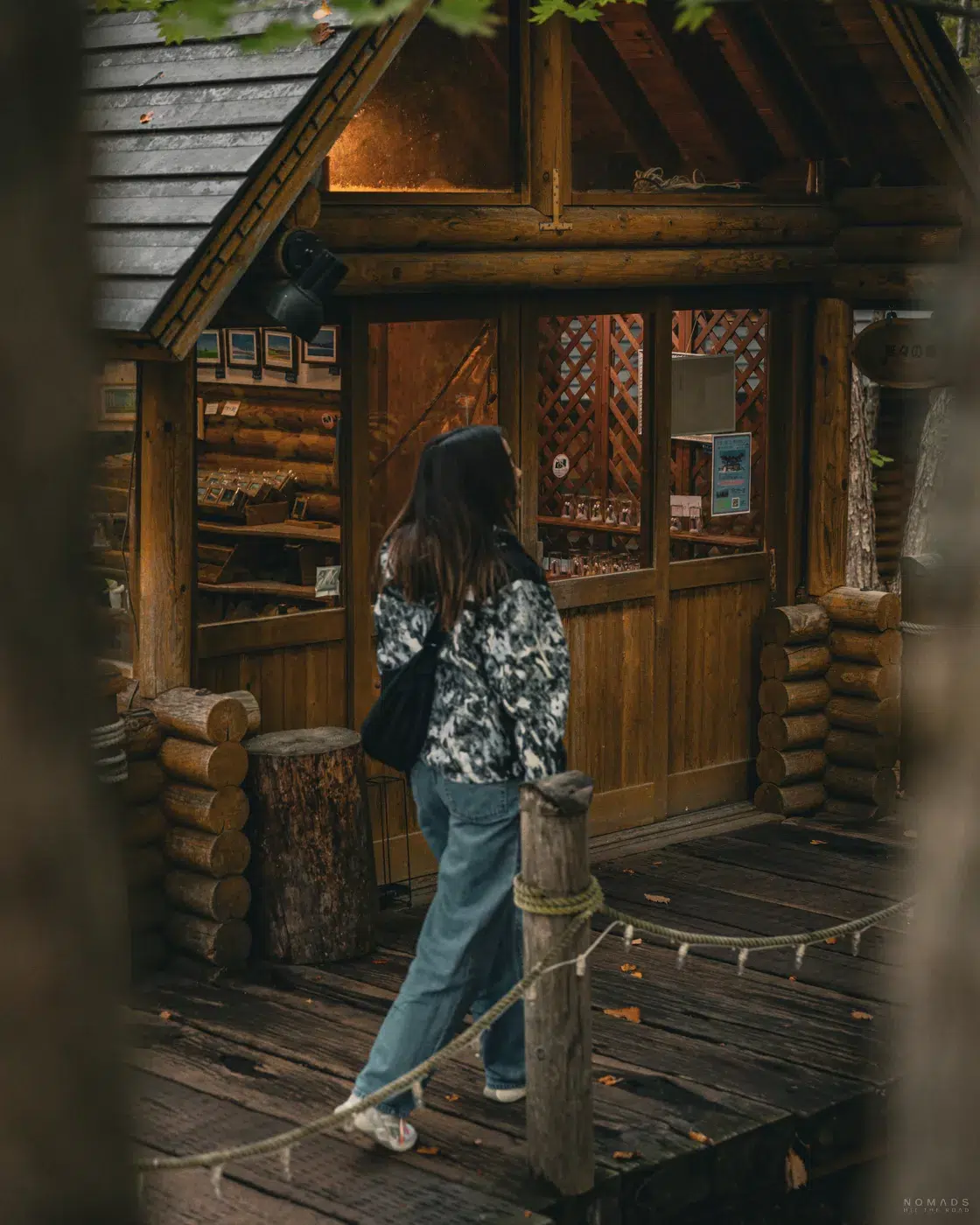 Besucherin vor einer beleuchteten Holzwerkstatt in der Ningle Terrace in Furano, gemütliche Atmosphäre im Wald