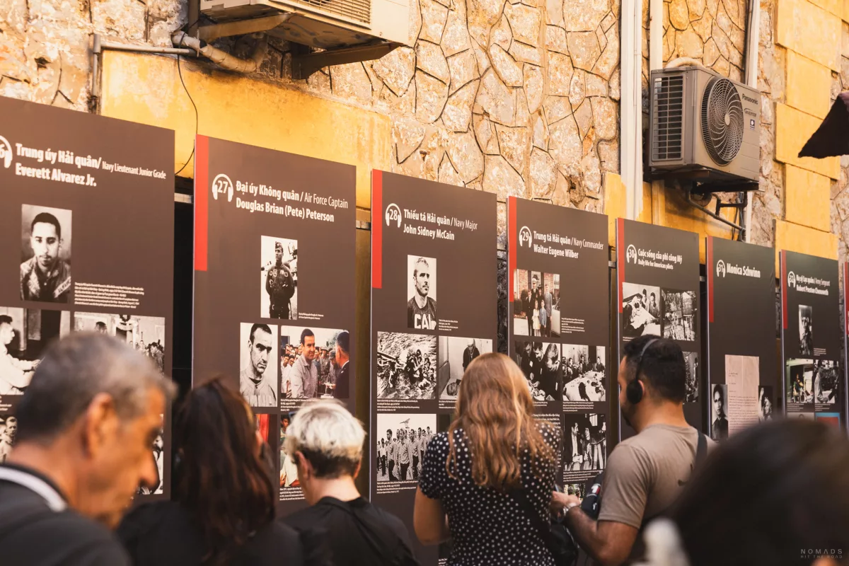 Bildstrecke mit historischen Fakten vor denen Menschen stehen im Hoa Lo Prison in Hanoi