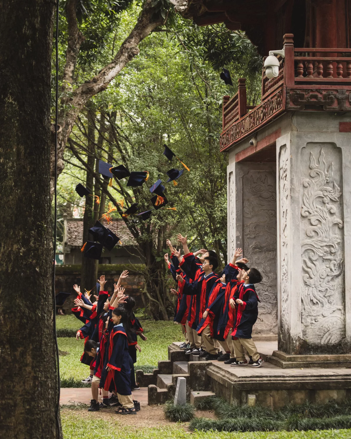 Schulkinder in Uniformen werfen Mützen in die Luft