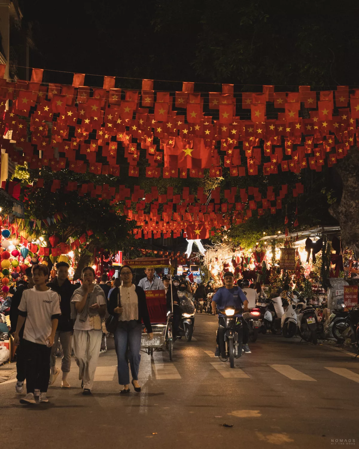 Straße in Hanoi, die überhangen mit Flaggen ist und Menschen durchlaufen