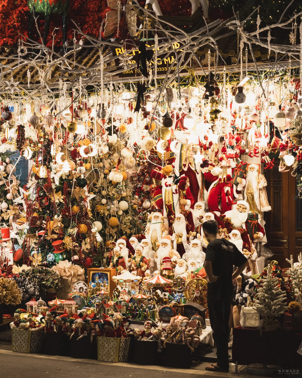 Leuchtende Weihnachtsdeko in einem Shop vor dem ein Mann steht