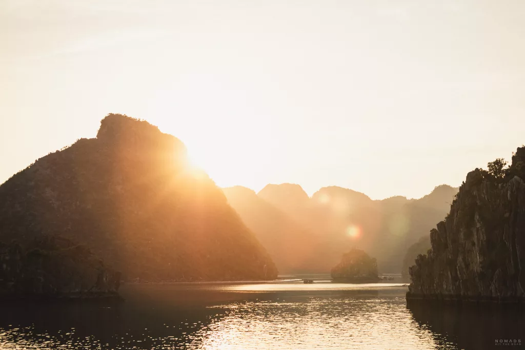 Sonne geht hinter den Felsen in der Halong Bay unter und gibt ein schönes Licht