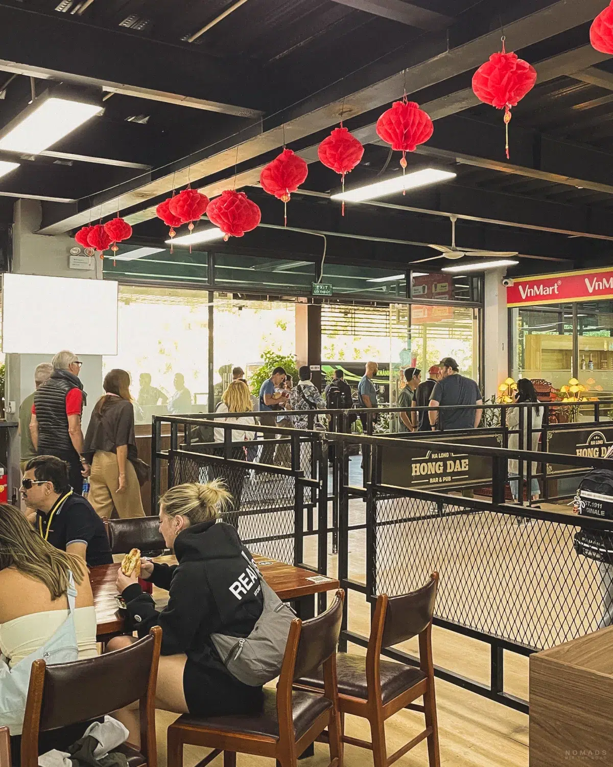 Menschen sitzen und stehen vor einem VinMart als letzter Stop vor der Halong Bay