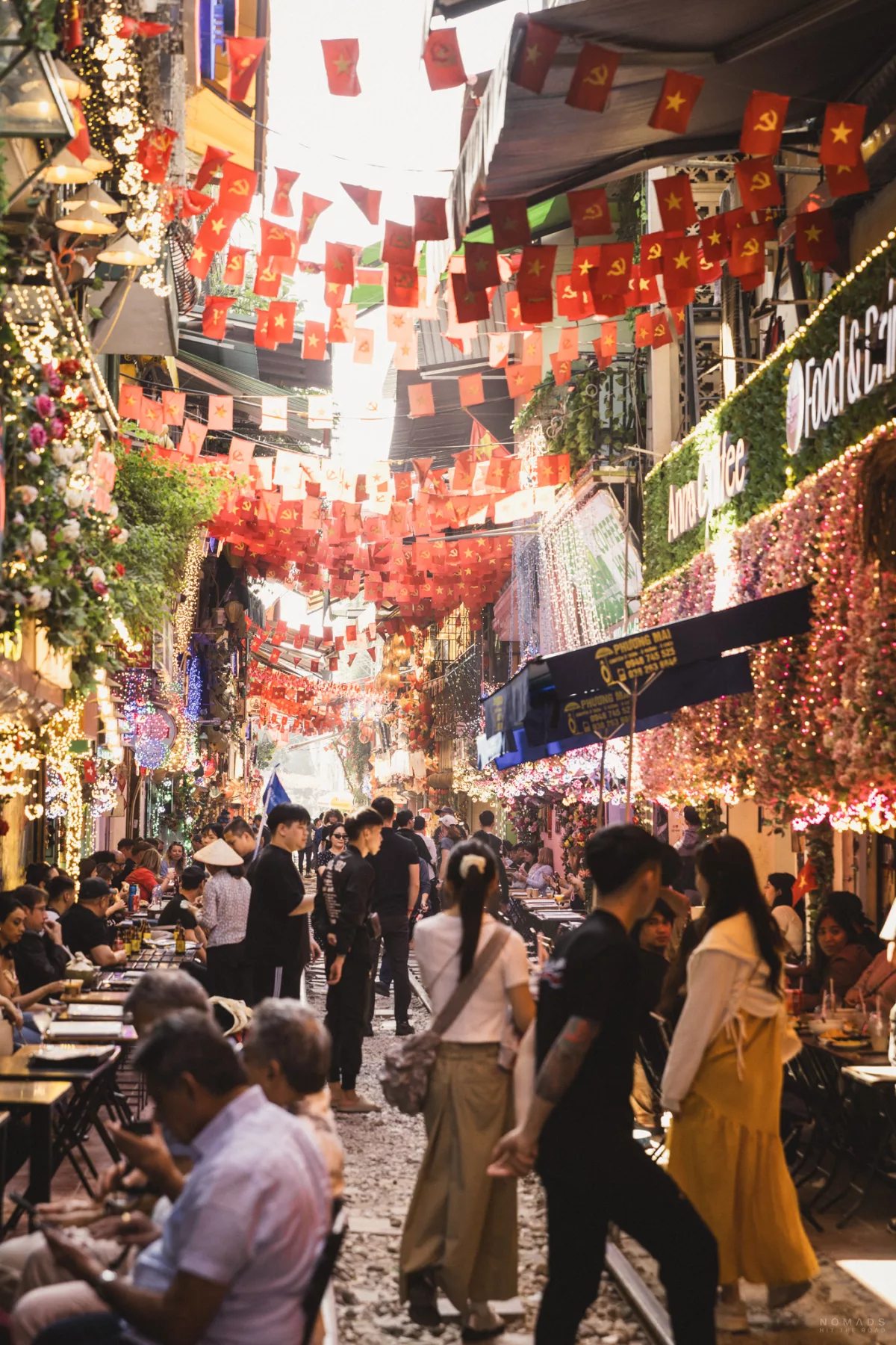 Menschen laufen auf einer Gleise zwischen Cafés herum