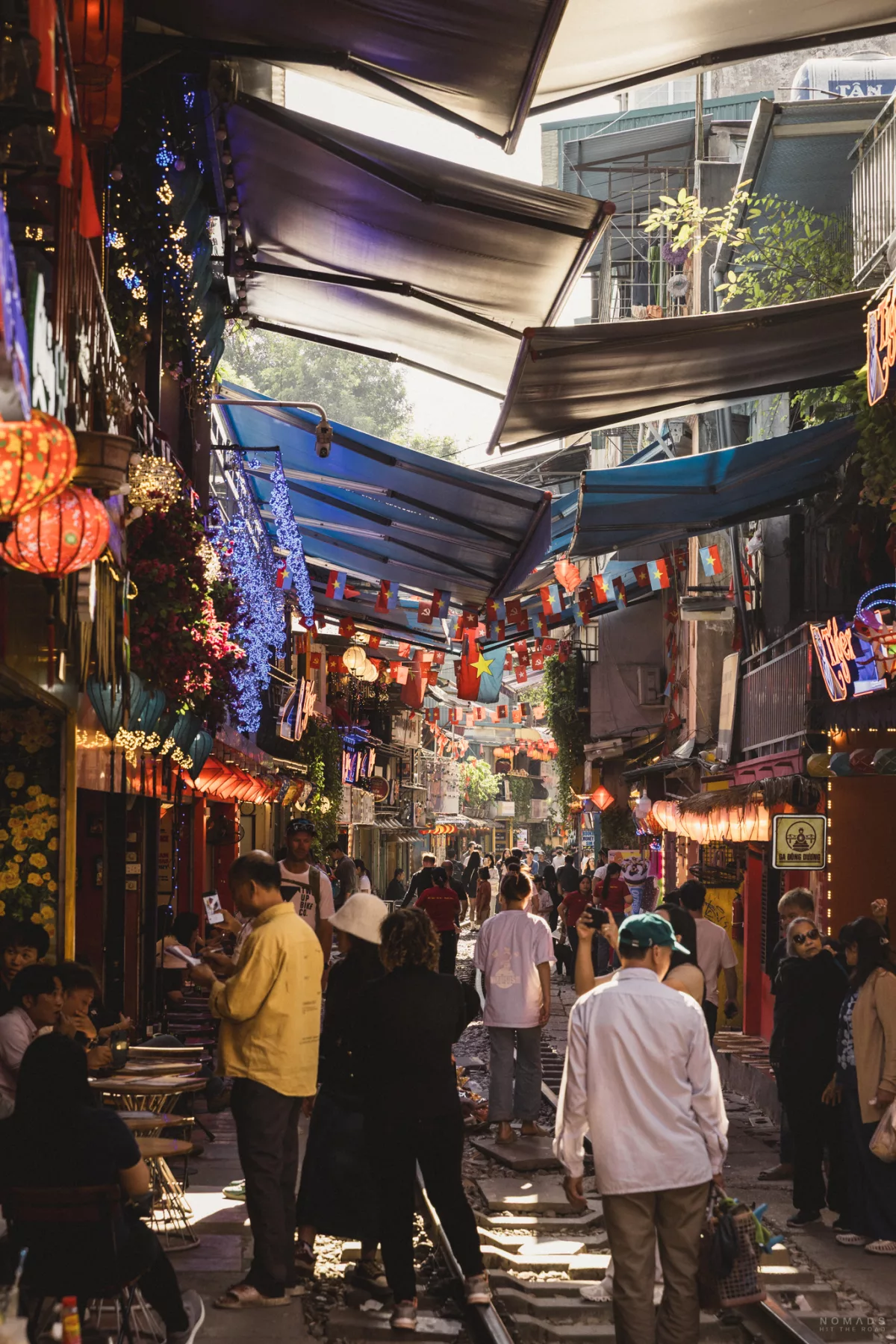 Menschen laufen auf einer Gleise zwischen Cafés herum