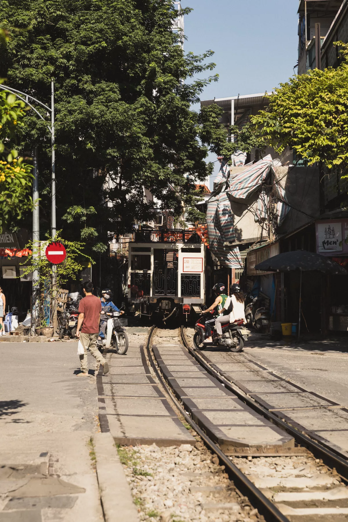 Zug von hinten, wie er wegfährt und Motorräder die Straße überqueren
