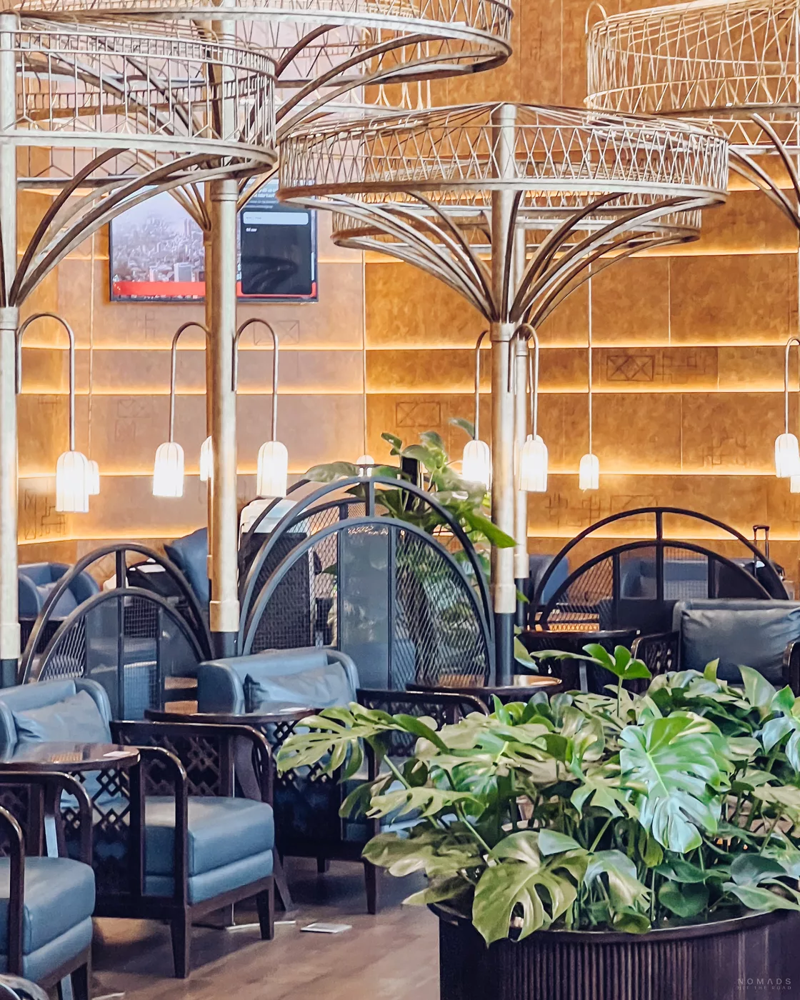 Eine exklusive Airport-Lounge mit modernen, blauen Sesseln und markanten, baumähnlichen Goldstrukturen an der Decke, die eine ruhige und hochwertige Atmosphäre ausstrahlen.