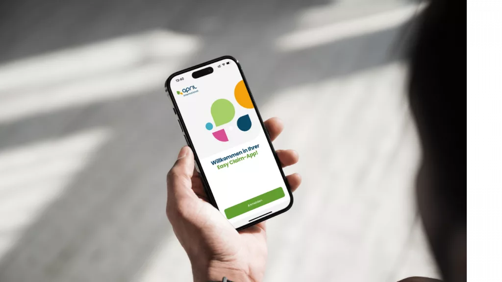 Foto über die Schulter einer Person auf das iPhone mit geöffneter Easy Claim App von April Krankenversicherung