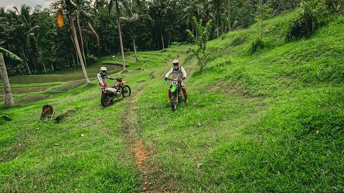 Zwei Menschen stehen auf einer grünen Fläche mit Dirt Bikes