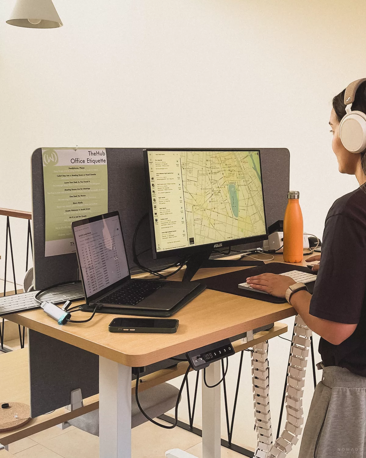 Frau mit Kopfhörern steht an einem Schreibtisch am PC im CoWorking Space von TheHub Pererenan