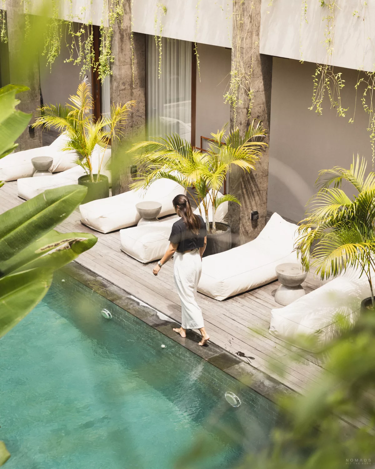 Frau läuft an einem Pool entlang mit Liegen und Pflanzen