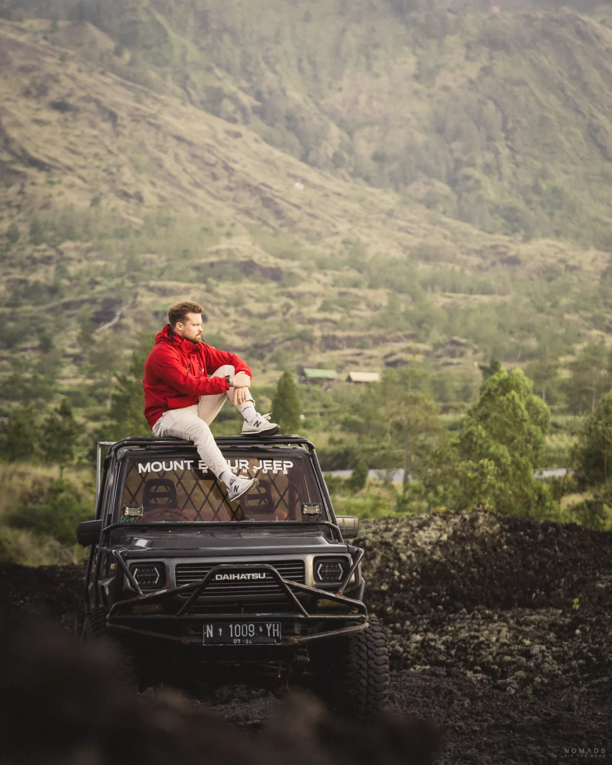 Mann sitzt auf dem Dach eines Auto auf der Mount Batur Jeep Tour