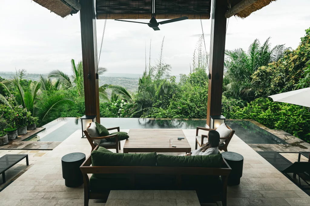 Frau sitzt auf einer Bank auf der Terrasse am Pool der Sanglung Villas & Suites