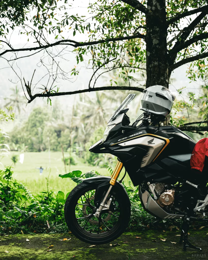 Motorrad steht am Straßenrand vor einem grünen Reisfeld in Munduk
