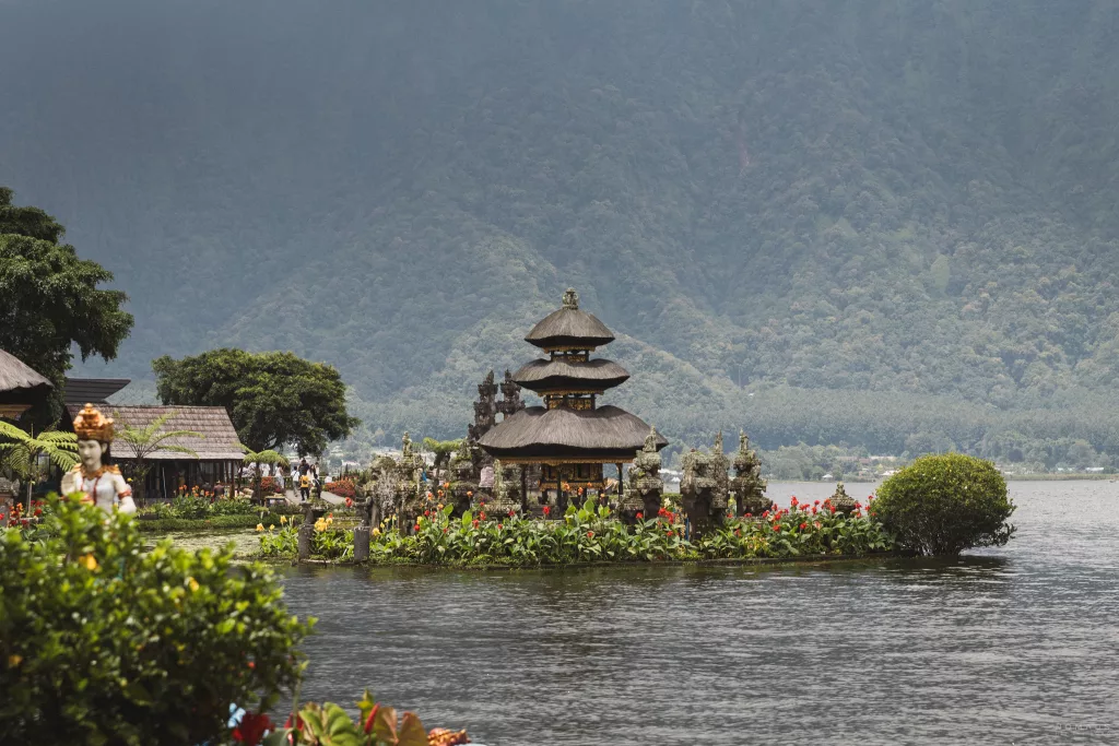 Pura Ulun Danu Bratan auf dem See mit grün bewachsenem Hang im Hintergrund