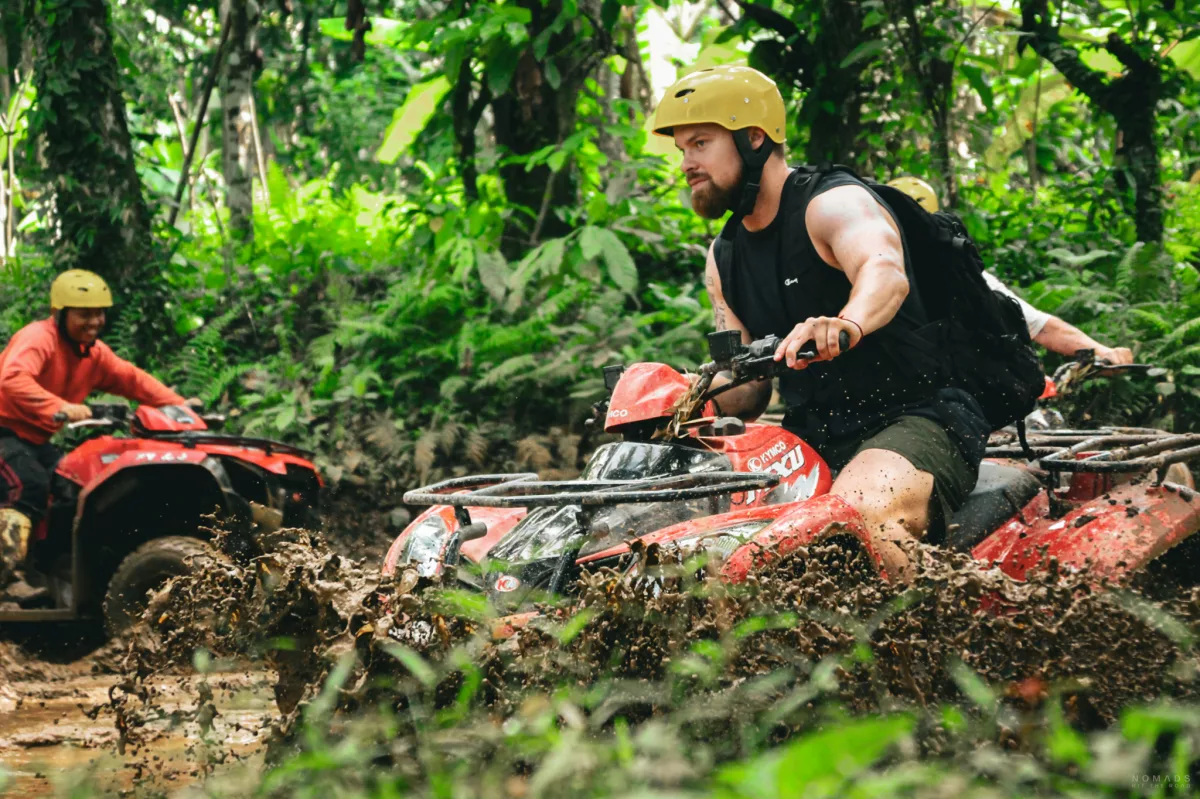 Mann fährt mit einem ATV durch eine Schlamm-Pfütze