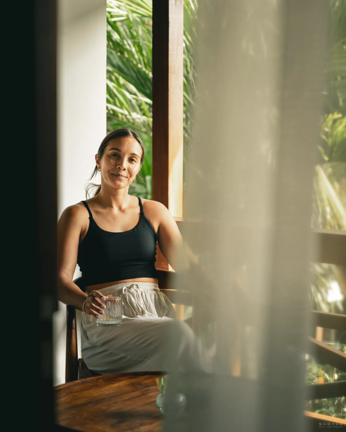 Frau sitzt mit einem Glas auf dem Balkon des Dinara Ubud