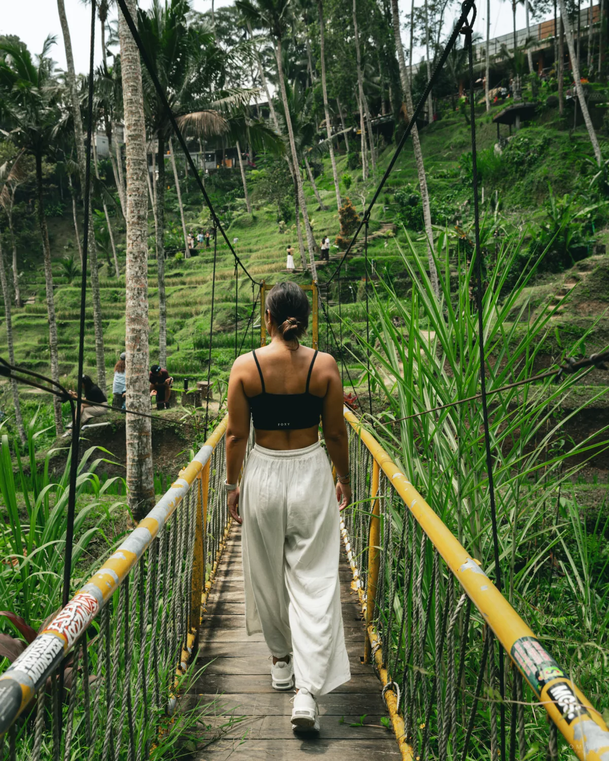 Frau läuft über eine Brücke mitten in den Reisfeldern von Tegallalang in Ubud