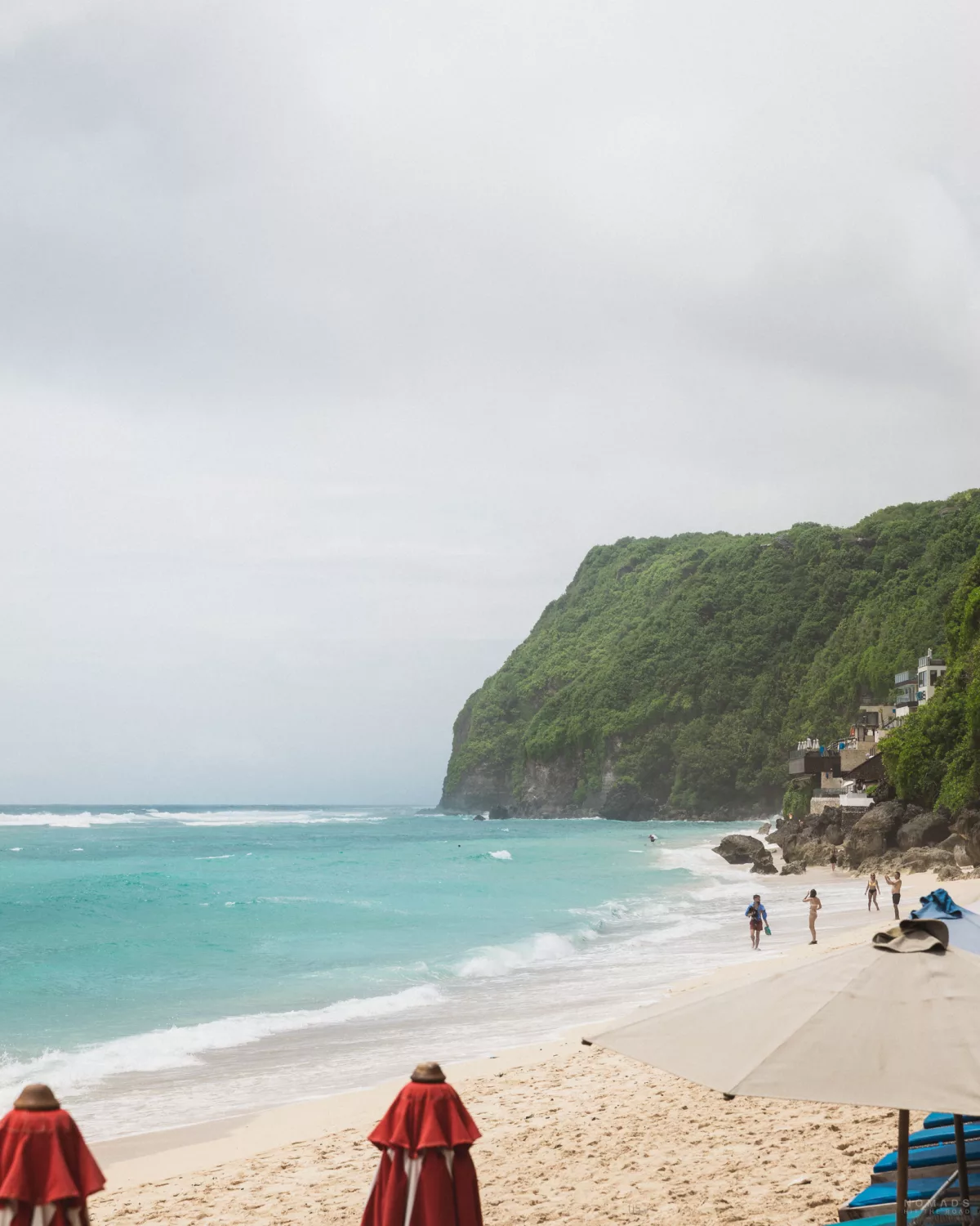 Wellen, die auf den Melasti Beach treffen der umgeben ist von bewachsenen Hängen